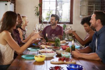 Six young adult friends sitting at table for a dinner party