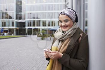 British Muslim Woman Texting On Mobile Phone Outside Office