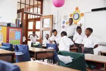 Teacher welcomes kids arriving to elementary school class