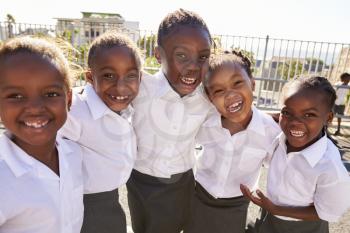 Young African schoolgirls in playground smiling to camera