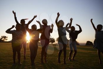 Silhouetted school kids jumping outdoors at sunset