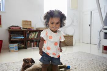 Portrait Of Happy Baby Girl Playing With Toys In Playroom