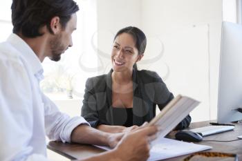 Man and woman with documents in an office, smiling, close up