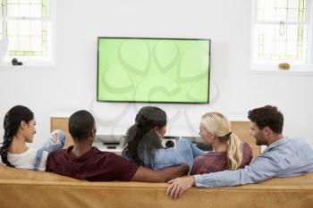 Rear View Of Group Of Young Friends Watching Television Together