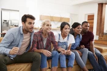 Group Of Young Friends Watching Sports On Television And Cheering