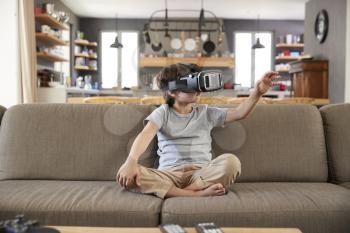Boy Sitting On Sofa Wearing Virtual Reality Headset
