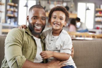 Portrait Of Father And Son Sitting On Sofa In Lounge Together