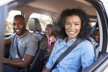 Young black family in a car on a road trip smiling to camera