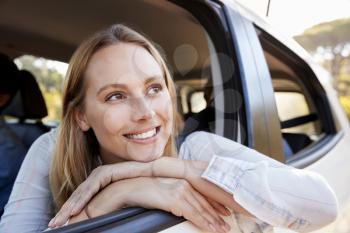 Happy young white woman looking out of a car window smiling