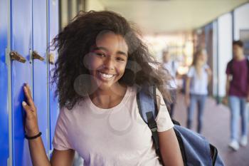 Portrait of black teenage girl by lockers in school corridor