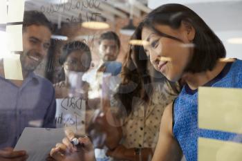 Businesswoman Writing Ideas On Glass Screen During Meeting