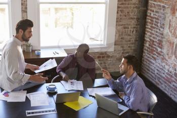 Group Of Businessmen Working Together In Boardroom