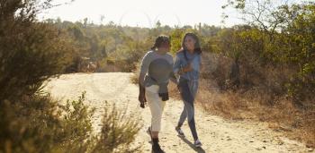 Mother And Adult Daughter Hiking Outdoors In Countryside