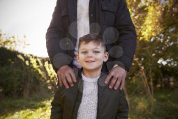 Portrait Of Boy With Father Standing In Autumn Garden