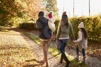 Rear View Of Family Enjoying Autumn Walk In Countryside