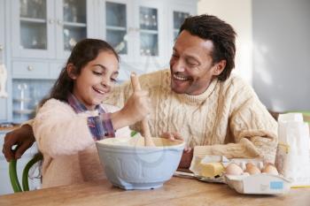 Father And Daughter Baking Cookies At Home Together