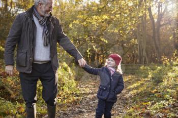 Grandfather And Granddaughter Enjoying Autumn Walk