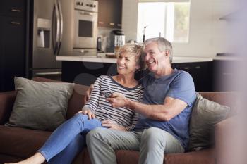 Senior white couple relaxing on couch watching television