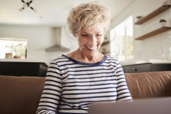 Senior white woman using laptop computer at home, close up