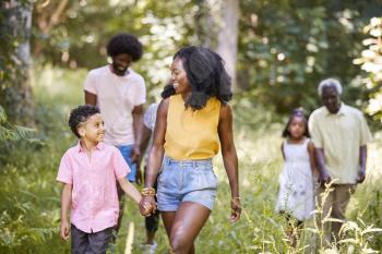 Black mother and son walking in woods looking at each other