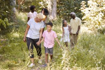 Black grandma walking with grandson and family, full length