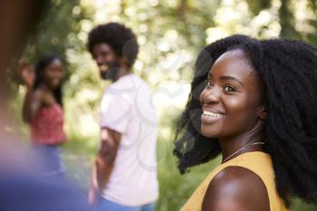 Young black woman in a forest with friends turning to camera