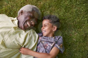 Boy and his granddad lying on grass, overhead close up