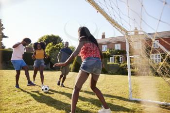 Two black adult couples playing football in garden