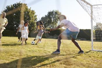 Multi generation black family playing football in a garden