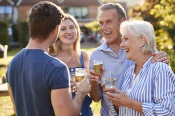 Parents With Adult Offspring Enjoying Outdoor Summer Drink At Pub