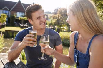 Couple Sitting At Table Enjoying Outdoor Summer Drink At Pub