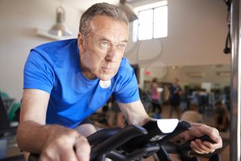 Senior Man Exercising On Cycling Machine In Gym
