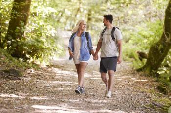 Couple Hiking Along Woodland Path In Lake District UK Together