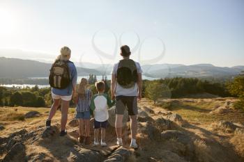 Rear View Of Family Standing At Top Of Hill On Hike Through Countryside In Lake District UK