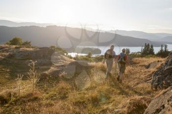 Rear View Of Senior Couple Walking On Top Of Hill On Hike Through Countryside In Lake District UK