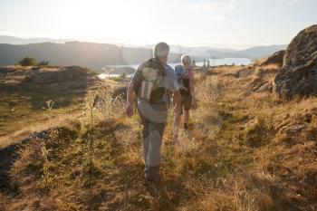 Rear View Of Senior Couple Walking On Top Of Hill On Hike Through Countryside In Lake District UK