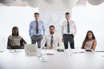 Portrait Of Businessmen And Businesswomen Meeting Around Table In Modern Boardroom