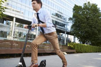 Young Businessman Commuting To Work Through City On Scooter