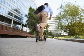 Young Businessman Commuting To Work Through City On Scooter