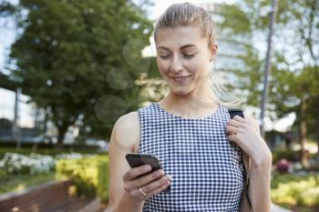 Businesswoman Walking To Work In City Looking At Mobile Phone