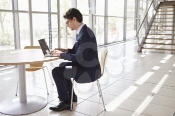 Young professional man using laptop, full length
