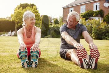 Healthy Senior Couple Exercising In Garden Together
