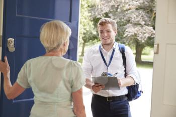 Senior woman opens door to male charity worker doing survey