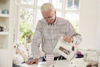 Senior man making cup of tea at home