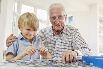 Senior man and grandson doing a jigsaw puzzle at home