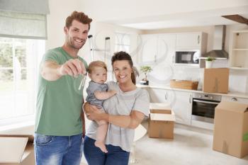 Portrait Of Family With Baby Holding Keys On Moving In Day