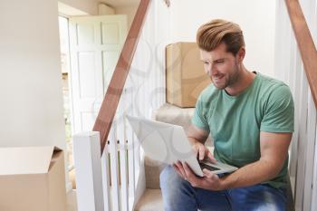 Man Moving Into New Home Looking At Personal Finances On Laptop