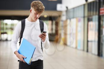 Male College Student Reading Text Message On Mobile Phone