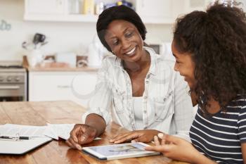 Mother Helps Teenage Daughter With Homework Using Digital Tablet