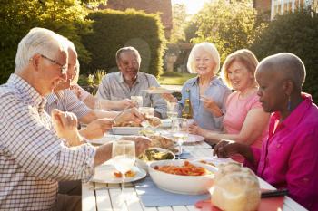 Group Of Senior Friends Enjoying Outdoor Dinner Party At Home